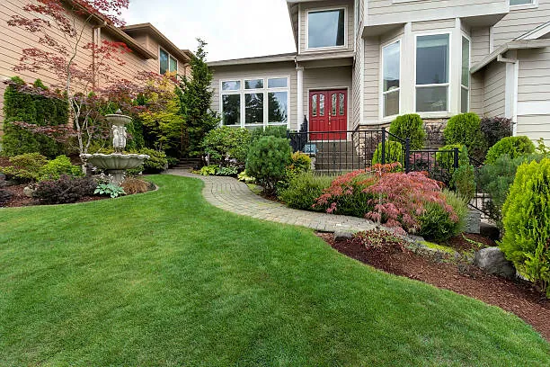 A front yard with a long curving planting bed of shrubs and flowers between the lawn and the house
