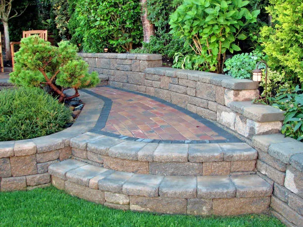A curved paver patio with a border band and a stone seat wall around it